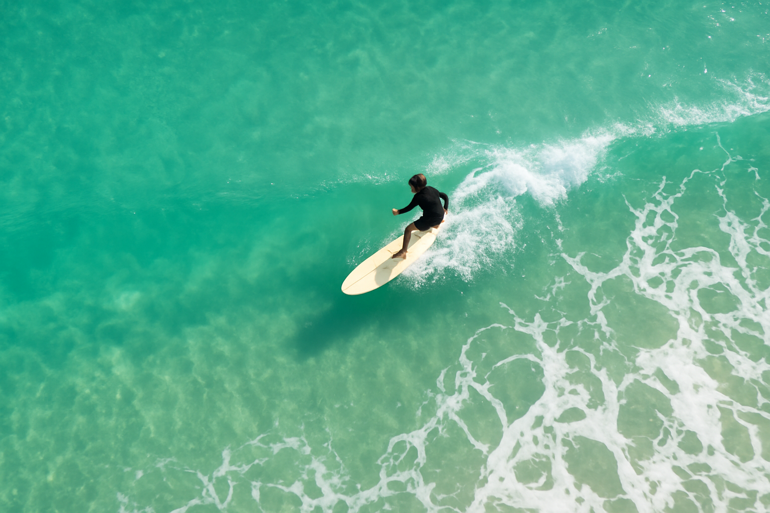 Aerial view of a surfer riding a wave after completing structured surf training sessions