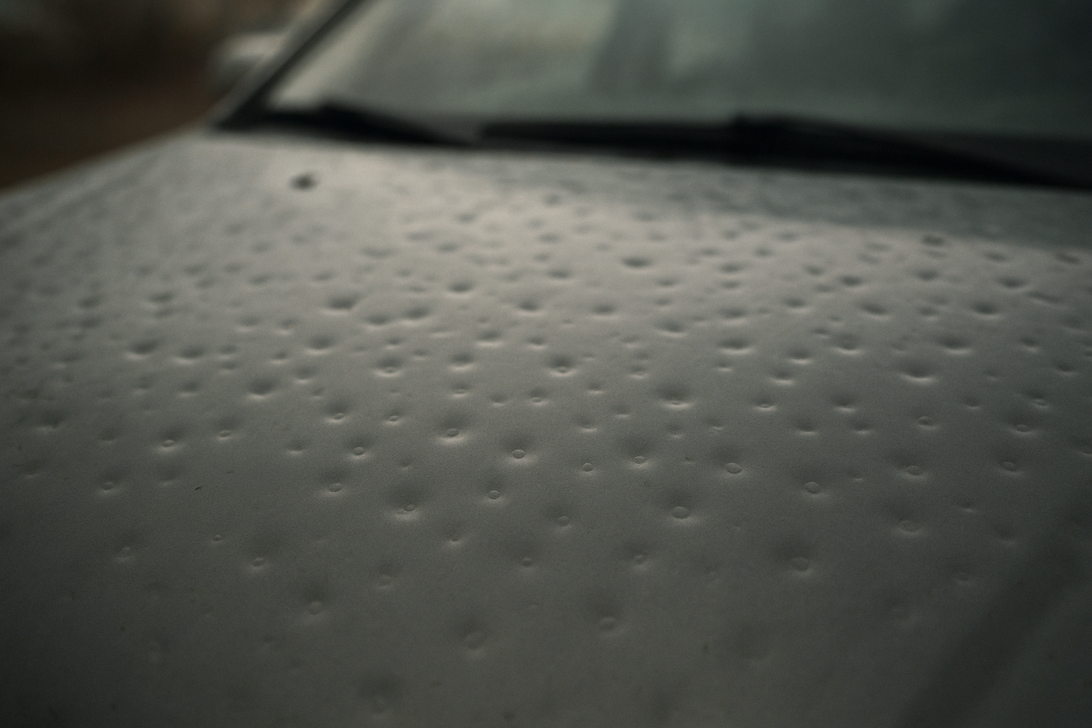 Auto hail damage repair Orange County technician assessing dented car hood after storm